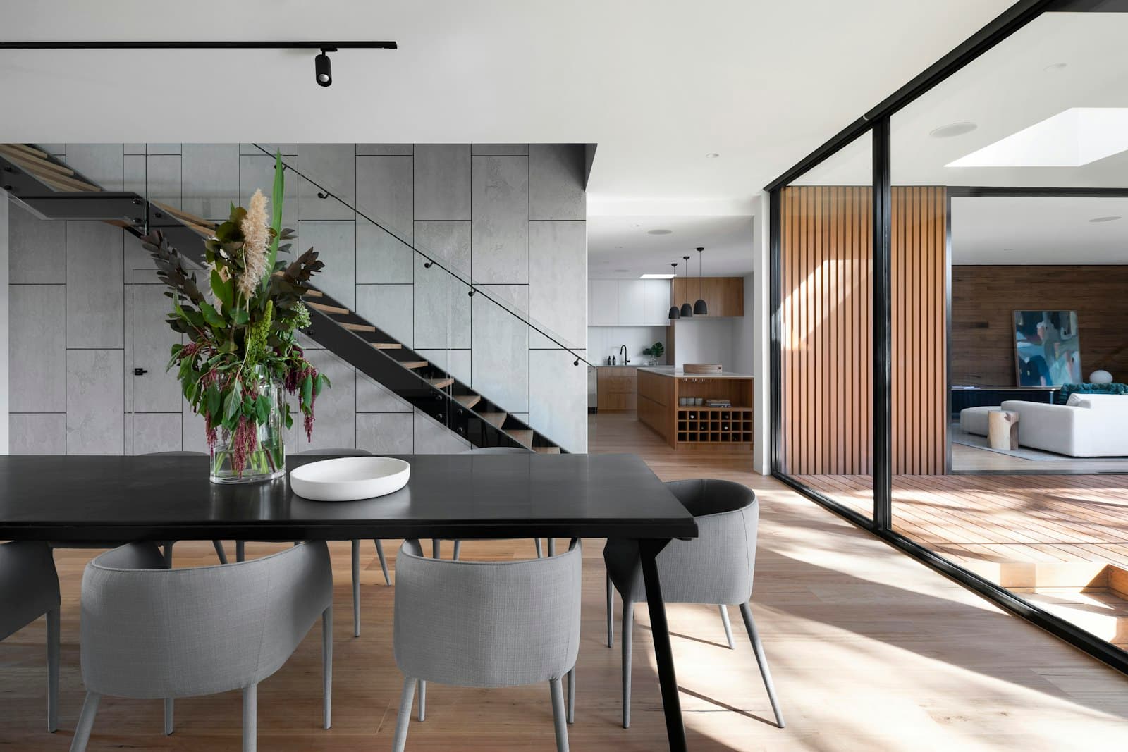 A calm, precisely built interior with a staircase and long table